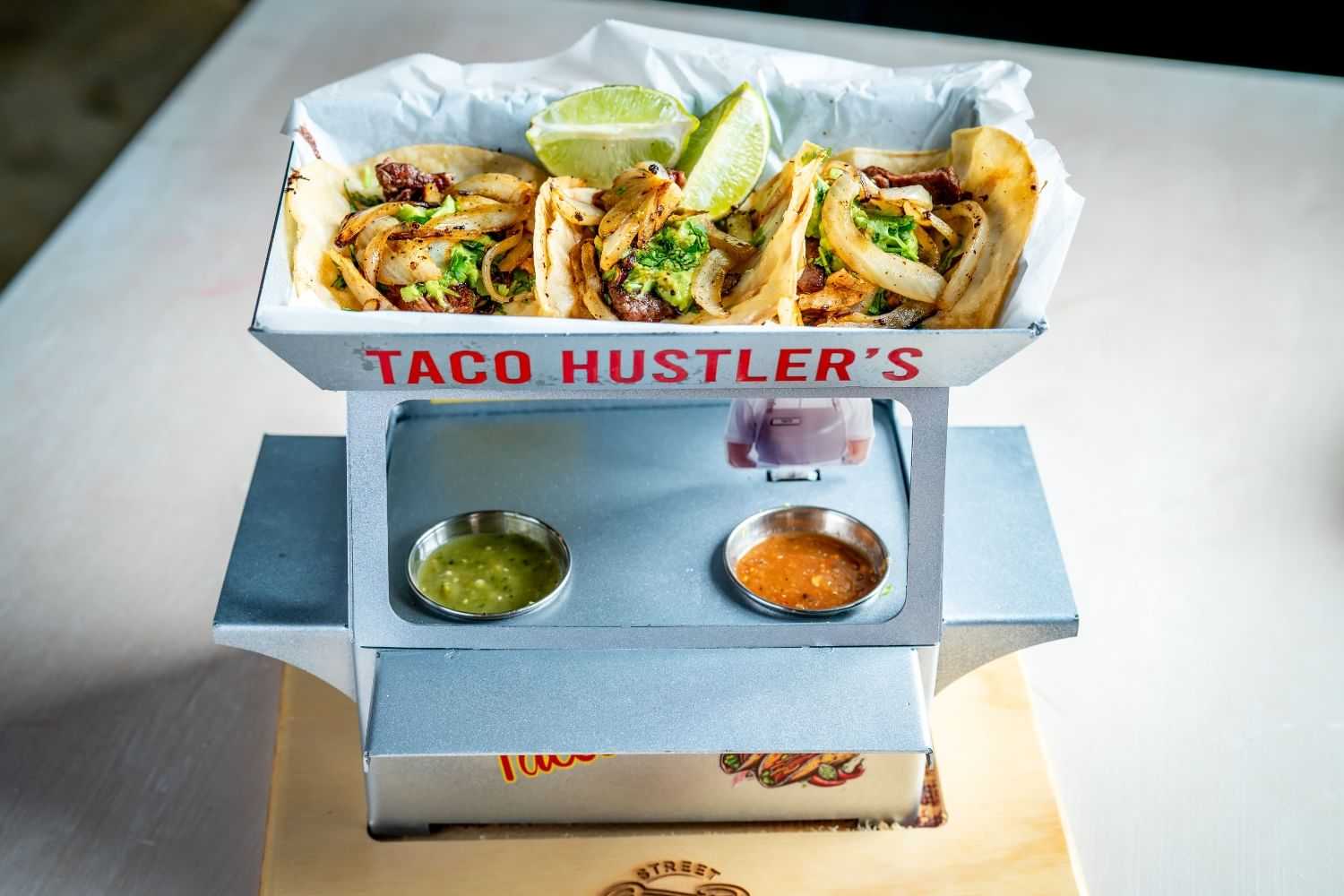 Tacos in a stylish holder with lime and sauces on the side.