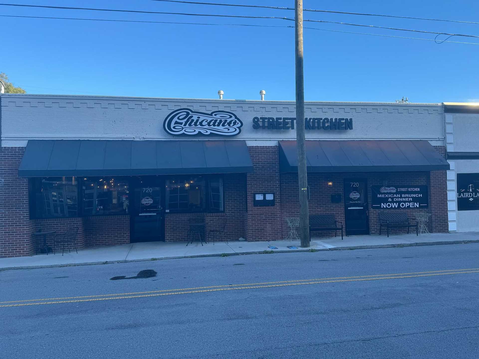 Storefront of Chicano Street Kitchen with brick facade and two large windows on a quiet street.