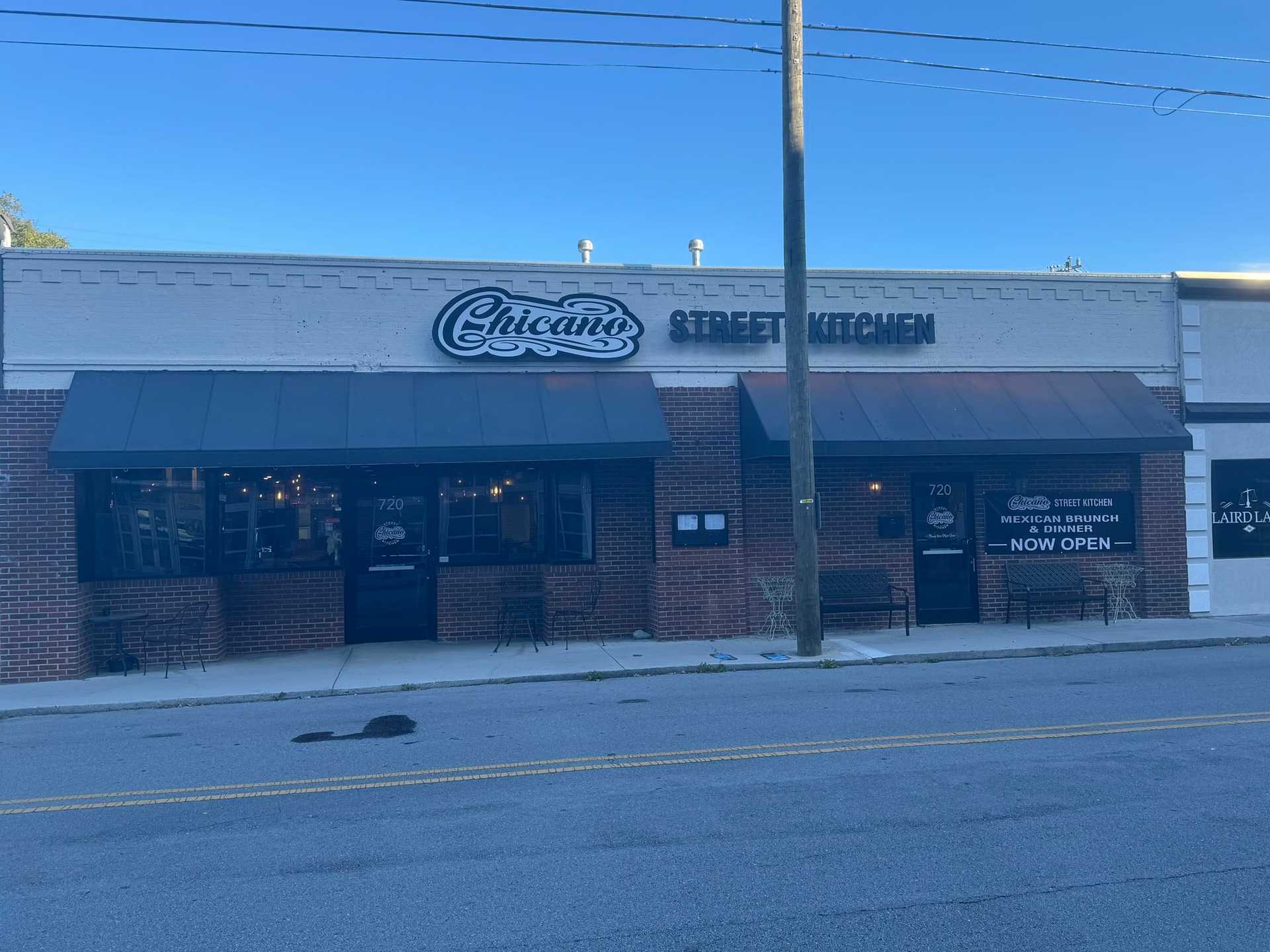 Storefront of Chicano Street Kitchen with brick facade and two large windows on a quiet street.